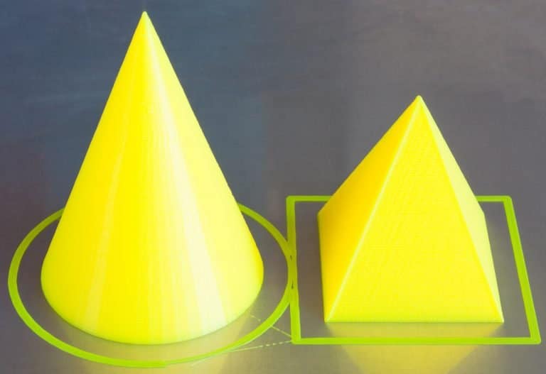 Two yellow cones, made of ABS material, are placed next to each other on a table.