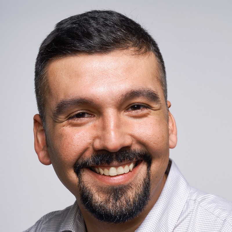 A man with a beard and a white shirt smiling.