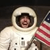 A man in an astronaut suit holding an american flag.