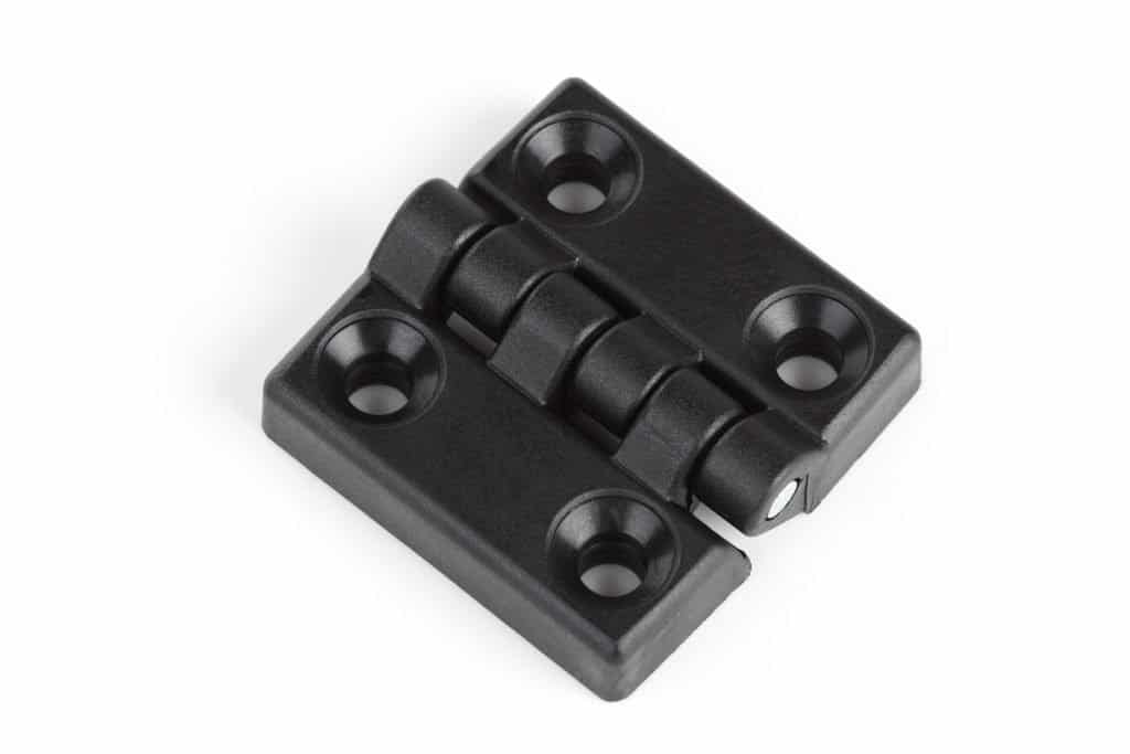 A pair of black plastic hinges on a white background made using injection molding materials.