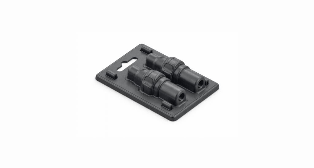 A retail packaging tray holding two black cylindrical plastic connectors—ideal for comparing compression molding vs injection molding—is displayed on a white background.