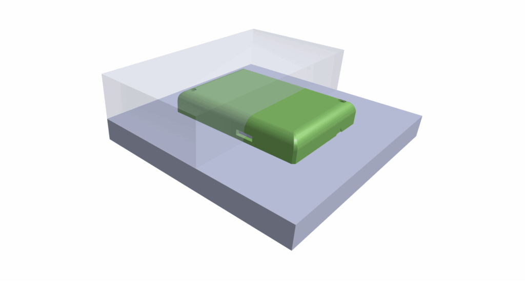 A green rectangular object, created using prototyping injection moldings, is placed inside a transparent, box-like enclosure on a gray platform.