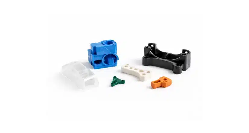 Six assorted plastic construction toy pieces in different shapes and colors—blue, black, clear, green, white, and orange—on a white background.