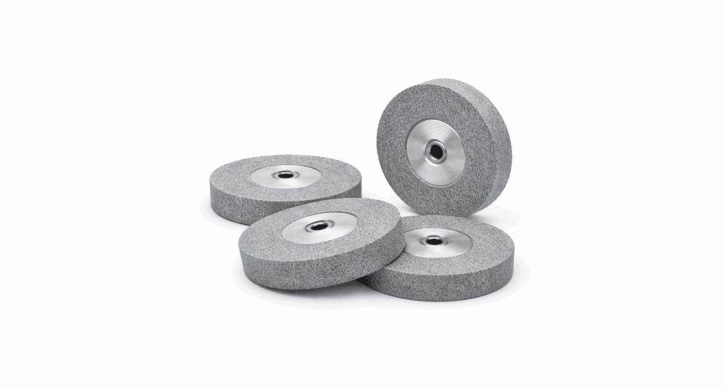 Four gray grinding wheels with metal centers are displayed, designed for cnc grinding, with three laying flat and one standing upright on a white background.