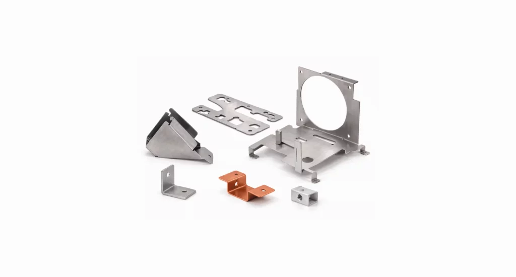 Six assorted metal brackets and mounting components, crafted by top precision manufacturing solutions companies, including silver and copper pieces, arranged on a plain white background.